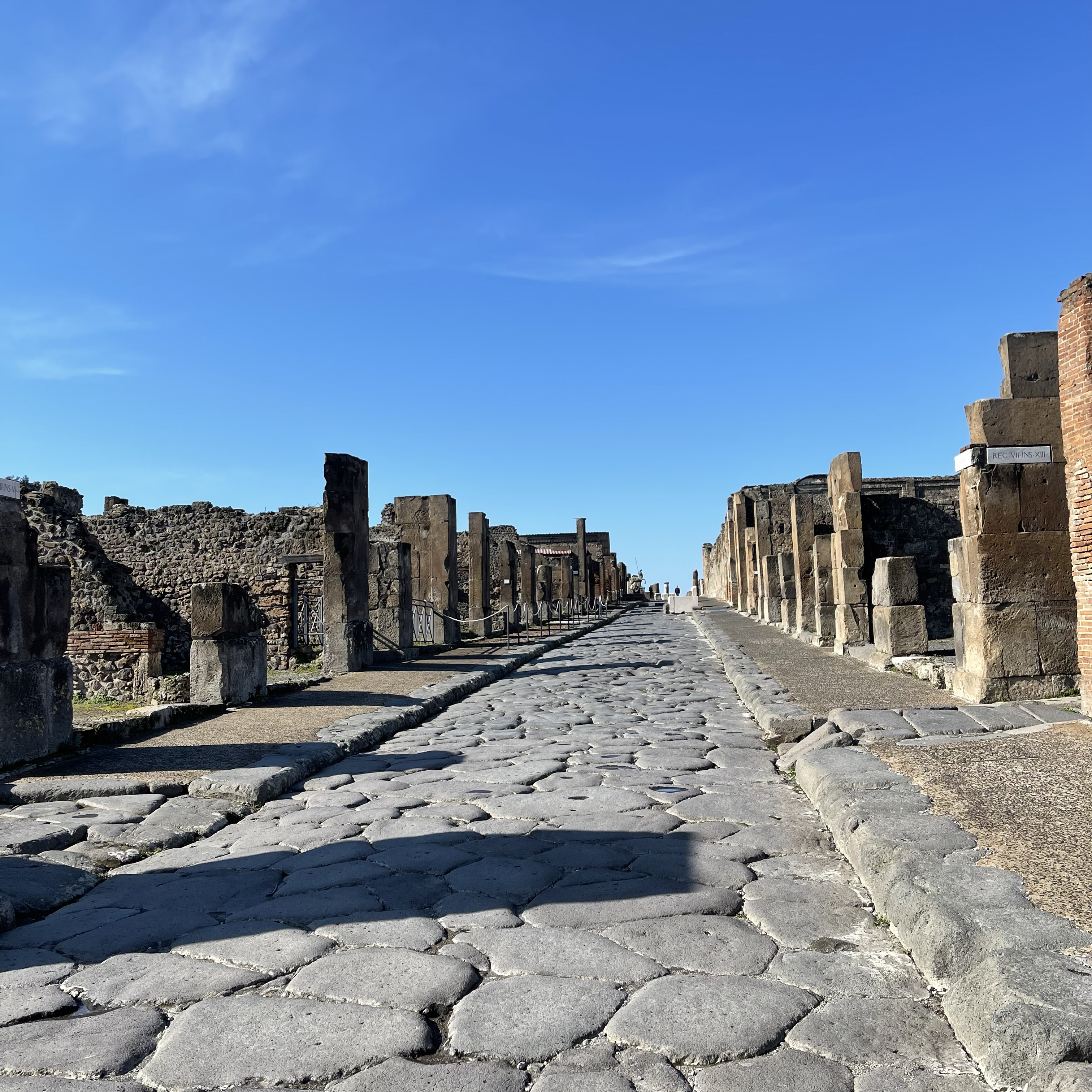 Straßen in Pompeji (2a−b) und Herculaneum (2c). Die polygonalen Steinplatten der Straßendecke fügten sich nahtlos aneinander. Über „Zebrastreifen“ konnten Fußgänger trockenen Fußes die Straßenseite wechseln (2b). Für die Karren wurden Joche im Überweg freigelassen.