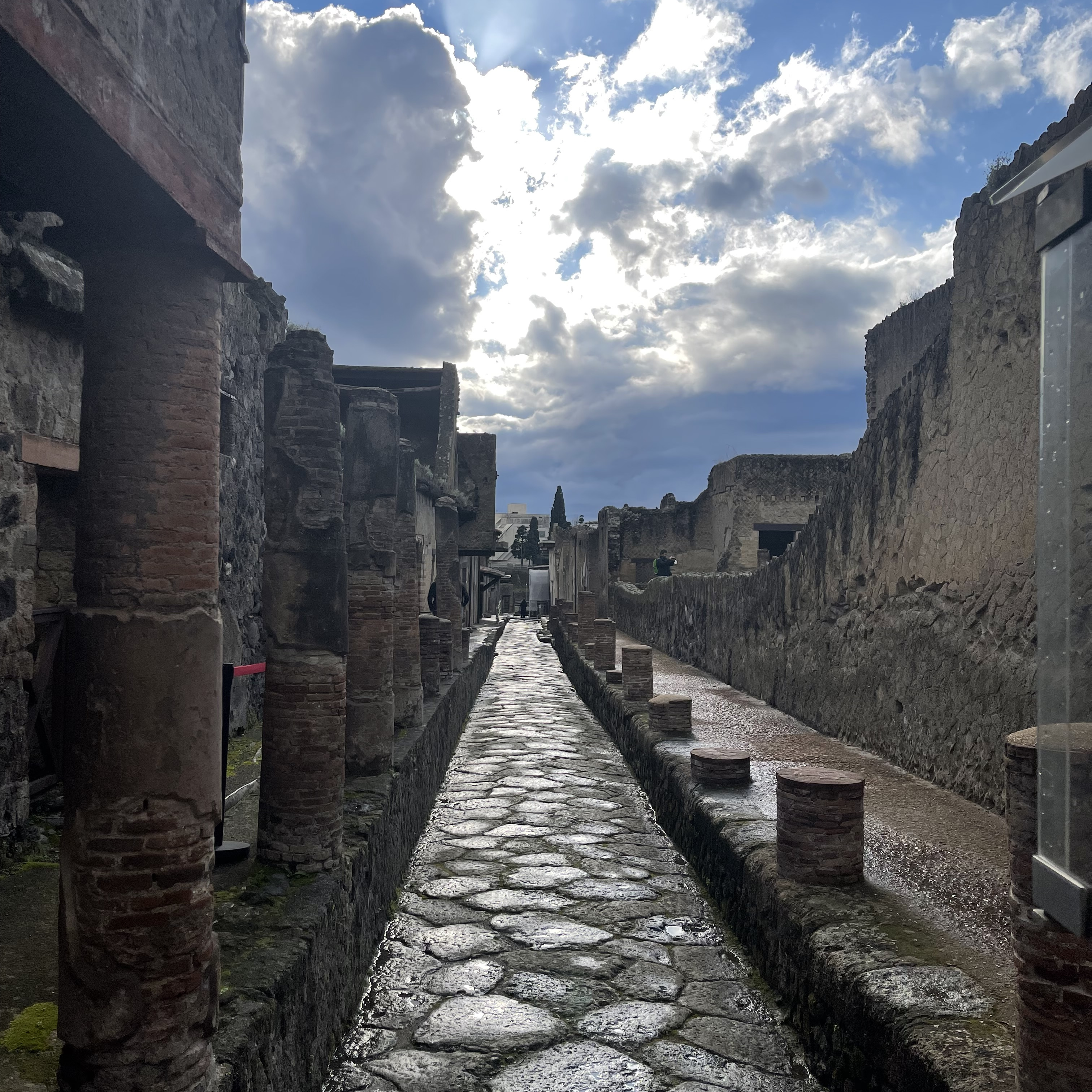 Straßen in Pompeji (2a−b) und Herculaneum (2c). Die polygonalen Steinplatten der Straßendecke fügten sich nahtlos aneinander. Über „Zebrastreifen“ konnten Fußgänger trockenen Fußes die Straßenseite wechseln (2b). Für die Karren wurden Joche im Überweg freigelassen.