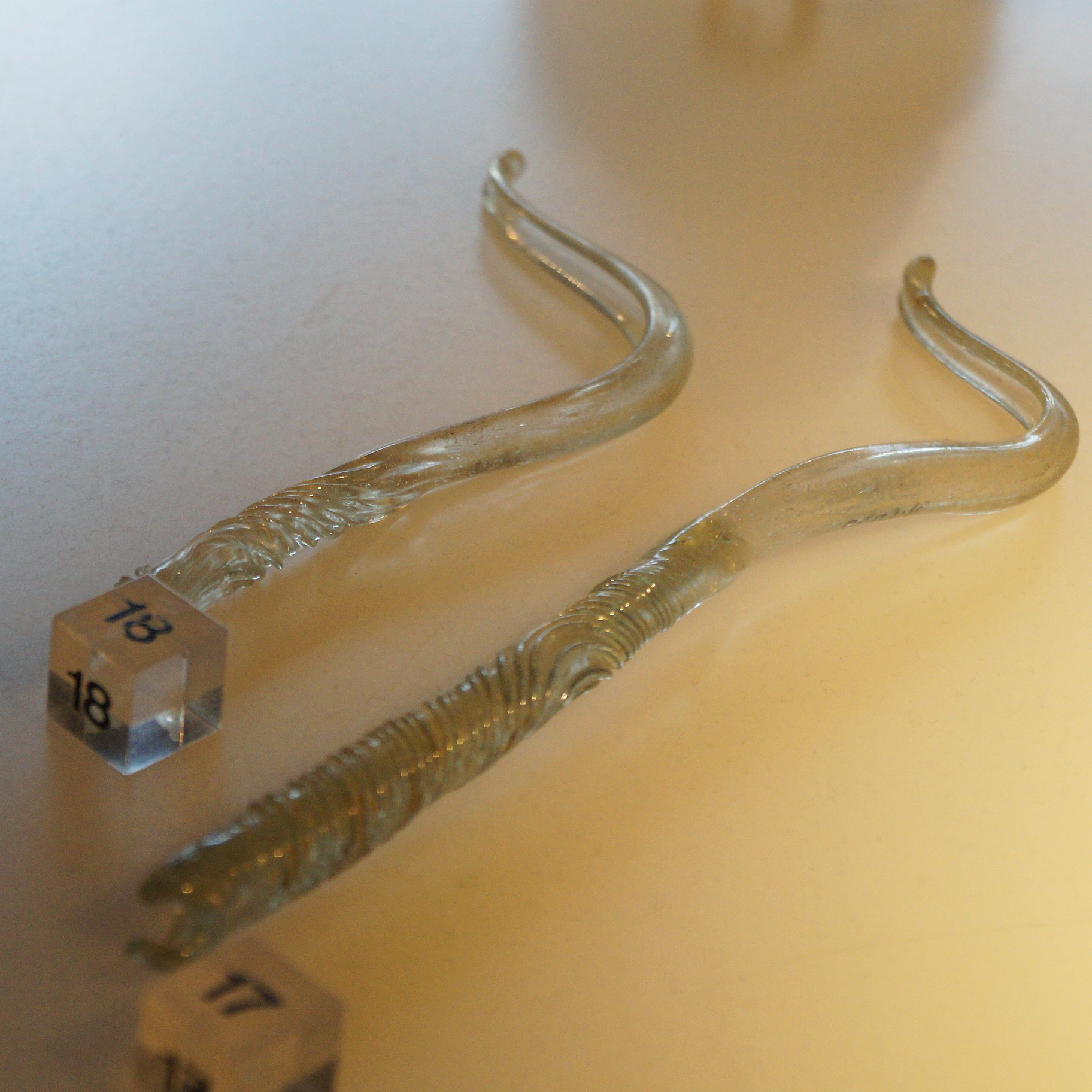 Foto zweier kostbarer Strigiles, sichelförmige "Abzieher" zum Reinigen der Haut, aus entfärbtem Glas. Eine beschädigte Öse deutet auf praktischen Gebrauch hin. Römisch-Germanisches Museum Köln. 