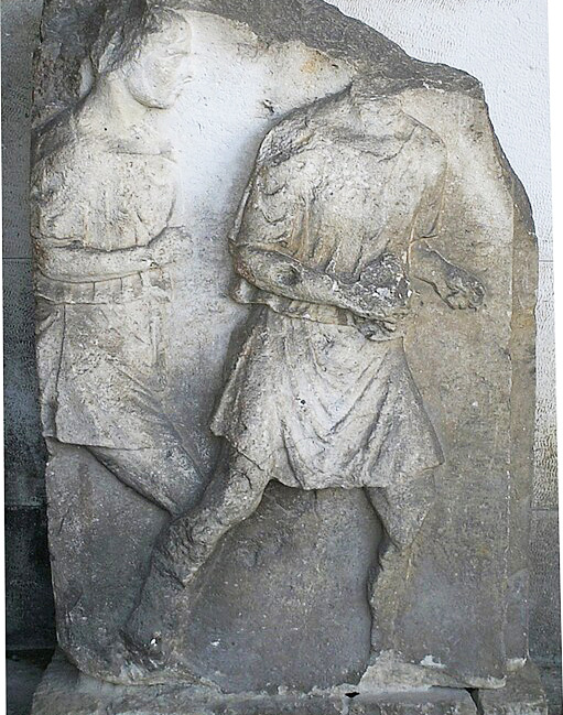 Foto eines römischen Steinreliefs mit der Abbildung zweier laufender Männer mit Tunika. 