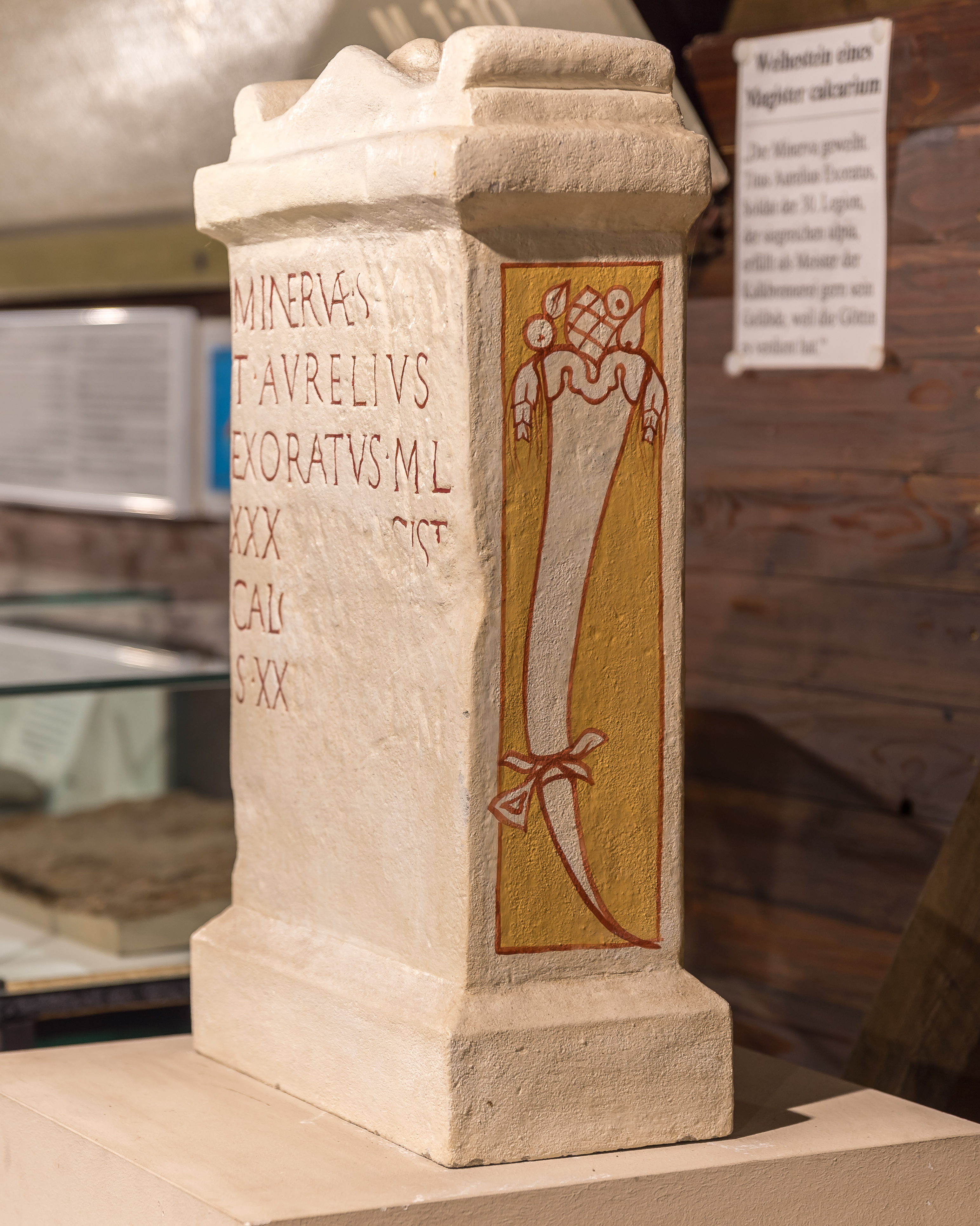 Foto der Kopie des steinernen Weihaltars des Titus Aurelius Exoratus an Minerva. Die Bemalung auf der Schmalseite zeigt ein Füllhorn mit Früchten und Pinienzapfen.