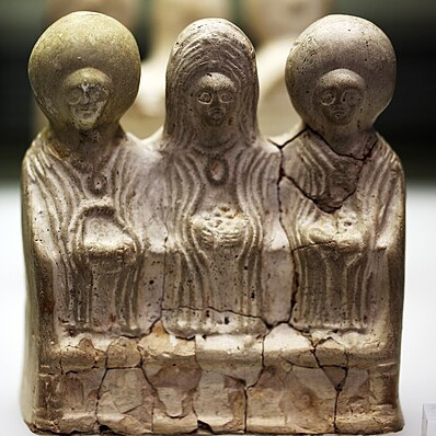 Foto einer 3-figurigen Statuetten-Kultgruppe mit drei Matronen. Die Oberfläche der Körper ist eingeschnitten, sodass die Gewänder eine Oberflächenstruktur erhalten.Terrakotte aus der Werkstatt des Kölner Töpfers Fabricius aus dem 2. Jh. n. Chr.. Römisch-Germanisches Museum Köln.