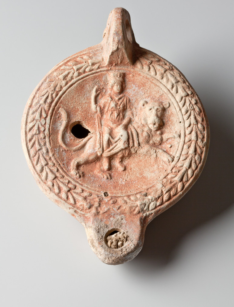 Kleine Öllampe aus Ton mit reliefartiger Darstellung der Kybele als Herrin der Tiere. Kennzeichen: Mauerkrone als Kopfschmuck und Löwe als Reittier. Römisch-Germanisches Museum Köln.