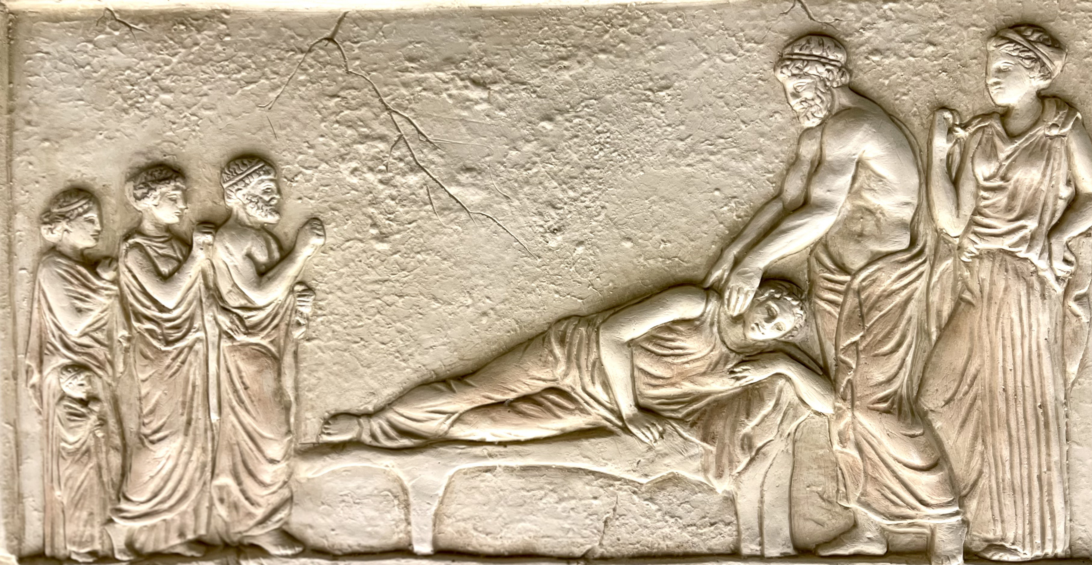 Aufnahme der Kopie eines Weihreliefs an Asklepios aus Piräus. Der Heilgott und seine Tochter untersuchen eine Patientin während des Tempelschlafs. 