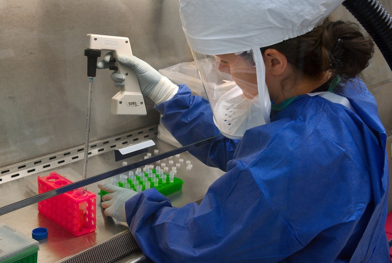 Fotografie einer Laborantin in Schutzkleidung beim Befüllen von Laborgefäßen.